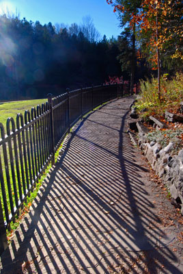a fence bordering the path casts dramtic shadows across the paving