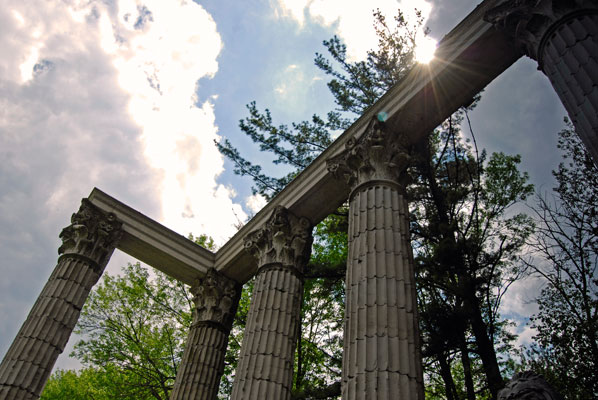 a view of clouds through stone columns