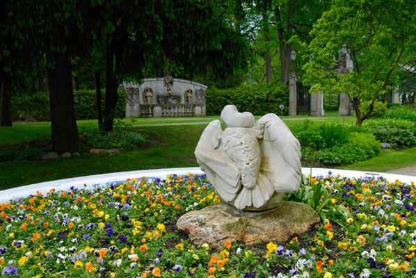 a sculpture in the centre of a large round planter full of pansies